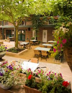 un patio al aire libre con mesas, sillas y flores en Vakantiewoningen-Pizzeria Blanckthys Voeren, en Voeren