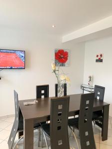 a dining room table with chairs and a television on a wall at Le saint genix in Saint-Genix-sur-Guiers