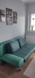 ein grünes Sofa im Wohnzimmer mit Fenster in der Unterkunft Apartament Północna in Brodnica