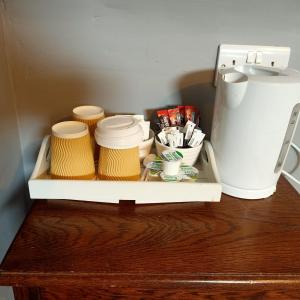 un estante con tazas y una cafetera sobre una mesa en The Milton Accommodation, en Elgin