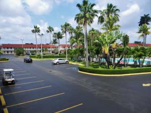 ein Parkplatz mit Autos, die eine Straße mit Palmen entlangfahren in der Unterkunft Fairway Inn Florida City Homestead Everglades in Florida City