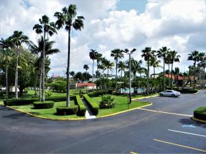 a parking lot with palm trees and a car on a street at Fairway Inn Florida City Homestead Everglades in Florida City