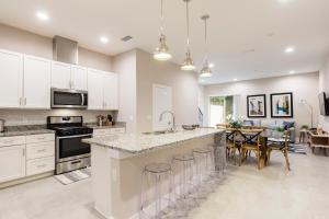 una cocina con armarios blancos y una isla de cocina con taburetes en Stylish Family Villa 5min Disney BBQ 1804ft, en Orlando