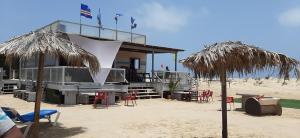 a building on the beach with chairs and umbrellas at AH Xamedu Sal Hostel in Santa Maria