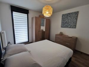 a bedroom with a white bed and a window at Les Ganivelles in Donville-les-Bains