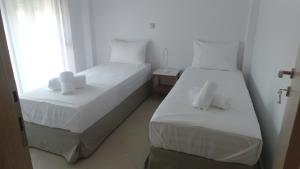 two beds in a white room with a window at Niovi Boutique Apartments in Afitos