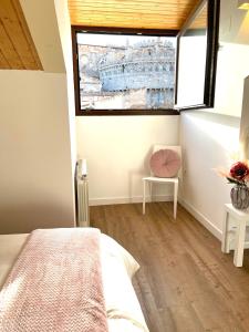 - une chambre avec un lit, une fenêtre et une chaise dans l'établissement Estrada Suites, à Ávila