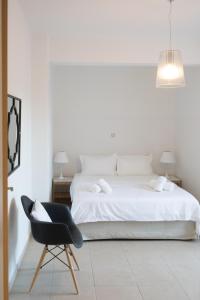a bedroom with a white bed and a black chair at Niovi Boutique Apartments in Afitos