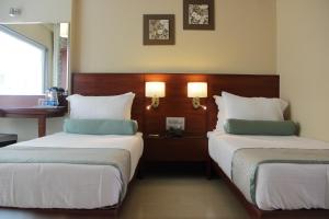 
a hotel room with two beds and two lamps at Hotel Green Olive in Aurangabad
