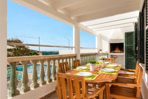 a balcony with a wooden table with chairs and a view at Villa Airosa by Villa Plus in Cala en Porter