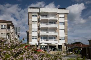 a tall white building with balconies on it at Pensión Venus in Nigrán