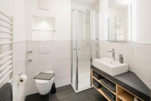 a white bathroom with a toilet and a sink at Apartmenthaus B3 in Norderney