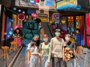 a group of people wearing face masks in front of a painting at mydeer backpacker in Tainan