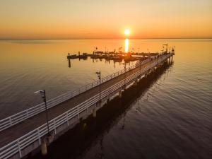 a pier with the sun setting over the water at Aparthotel Anchoria BlueApart in Mechelinki