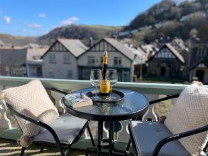 a bottle of wine and two glasses on a table on a balcony at Southcliffe B&B in Lynton