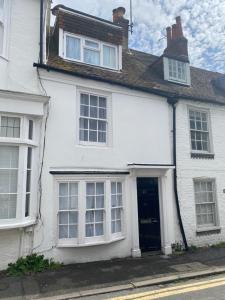 a white house with a door and windows at Salt Life Cottage in Brighton & Hove