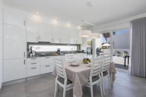 een keuken met een tafel en stoelen en een keuken met witte kasten bij Villa Dona Julia by Villa Plus in Carvoeiro