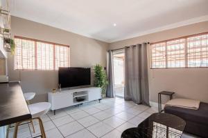 a living room with a flat screen tv and a couch at Beautiful and Modern apartment close to Menlyn in Pretoria