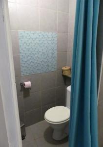 La salle de bains est pourvue de toilettes et d'un rideau de douche bleu. dans l'établissement Un pied-à-terre au centre de Papeete, à Papeete
