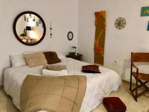 1 dormitorio con 1 cama blanca grande y espejo en La casa del Sur, en Granada