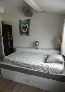 ein Bett in einem Schlafzimmer mit einer weißen Wand in der Unterkunft Un pied-à-terre au centre de Papeete in Papeete