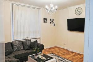a living room with a couch and a clock on the wall at Glasgow Southside: Cosy 2 Bedroom Apartment in Glasgow