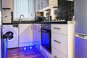 a kitchen with purple cabinets and a washer and dryer at Glasgow Southside: Cosy 2 Bedroom Apartment in Glasgow