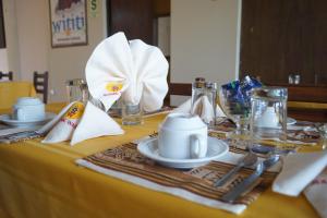 a table with a yellow table cloth with plates and silverware at Sumac wasi in Chivay