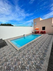 a swimming pool in front of a building with a house at Suítes Privativas em Guriri in Guriri