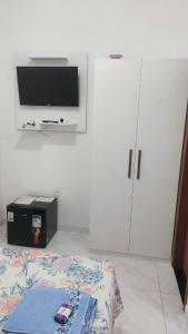um quarto com uma televisão, uma cama e um armário em Suítes Privativas em Guriri em Guriri