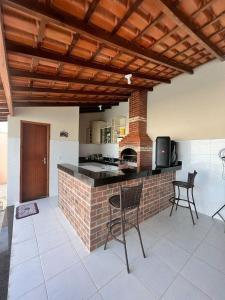 a kitchen with a bar with chairs and a table at Suítes Privativas em Guriri in Guriri