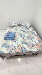 Una cama con una manta de flores con un bolso. en Suítes Privativas em Guriri, en Guriri