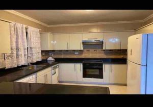 a kitchen with white cabinets and a white refrigerator at Luxurious and Modern 3 Bedroom Maadi Apartment in Cairo