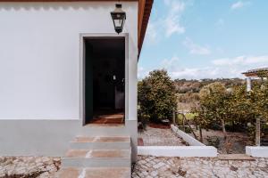 a door to a white house with a pathway at Cá Vamos HORTACASA PORTUGAL in Santiago do Cacém