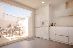 a kitchen with white cabinets and a table with chairs at Real de La Barrosa 46 in Chiclana de la Frontera