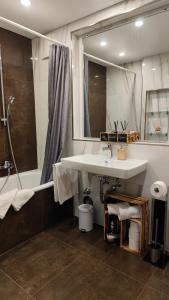 a bathroom with a sink and a mirror and a tub at Park Appartements in Badenweiler