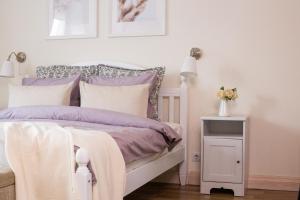 1 dormitorio con 1 cama con almohadas moradas y blancas en Provance Apartment, en Liepāja
