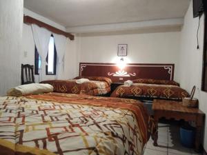 1 dormitorio con 2 camas y mesa en Hotel Casolia, en Quetzaltenango