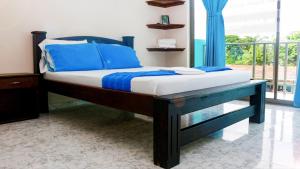 a bedroom with a bed with blue pillows and a balcony at Hotel Reserva Aguamarina in Playa Ladrilleros