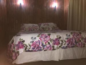 uma cama com lençóis e almofadas florais cor-de-rosa e roxo em Cabañas en Termas de Chillán em Recinto