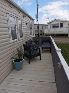 a wooden deck with two benches and a house at Riverside 11 PARKDEAN South Beach Heacham in Heacham