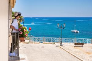 Un uomo in piedi su un balcone che guarda l'oceano di Hotel Al Madarig a Castellammare del Golfo