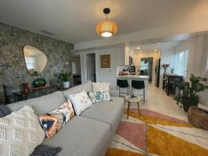 uma sala de estar com um sofá cinzento e uma cozinha em Jungle Cottage with luxury pool, hot tub and more! em Lake Worth