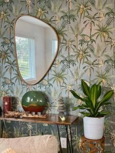 einen Spiegel und einen Tisch mit Pflanze in einem Zimmer in der Unterkunft Jungle Cottage with luxury pool, hot tub and more! in Lake Worth