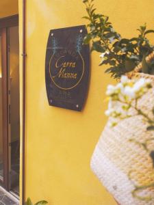 a sign on the side of a yellow wall with a plant at Locanda Carra Manna in Sassari