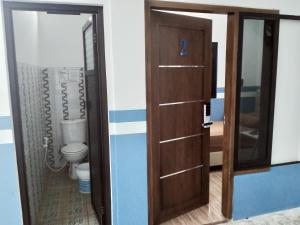 a bathroom with a wooden door and a toilet at PENGINAPAN BANYU BIRUKu in Kota-anyar