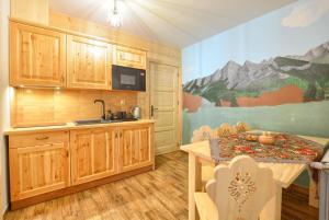 a kitchen with wooden cabinets and a table with chairs at Dom Pod Lipą in Brzegi