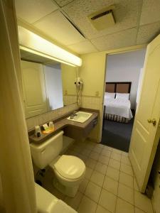 a bathroom with a toilet and a sink and a bed at Heritage Inn & Suites in Niagara Falls