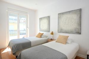 2 camas en una habitación blanca con ventana en Enjoy the Sunny Balcony, By TimeCooler en Lisboa