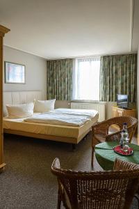 a bedroom with a bed and a table and chairs at Ostseehotel Neubukow in Neubukow